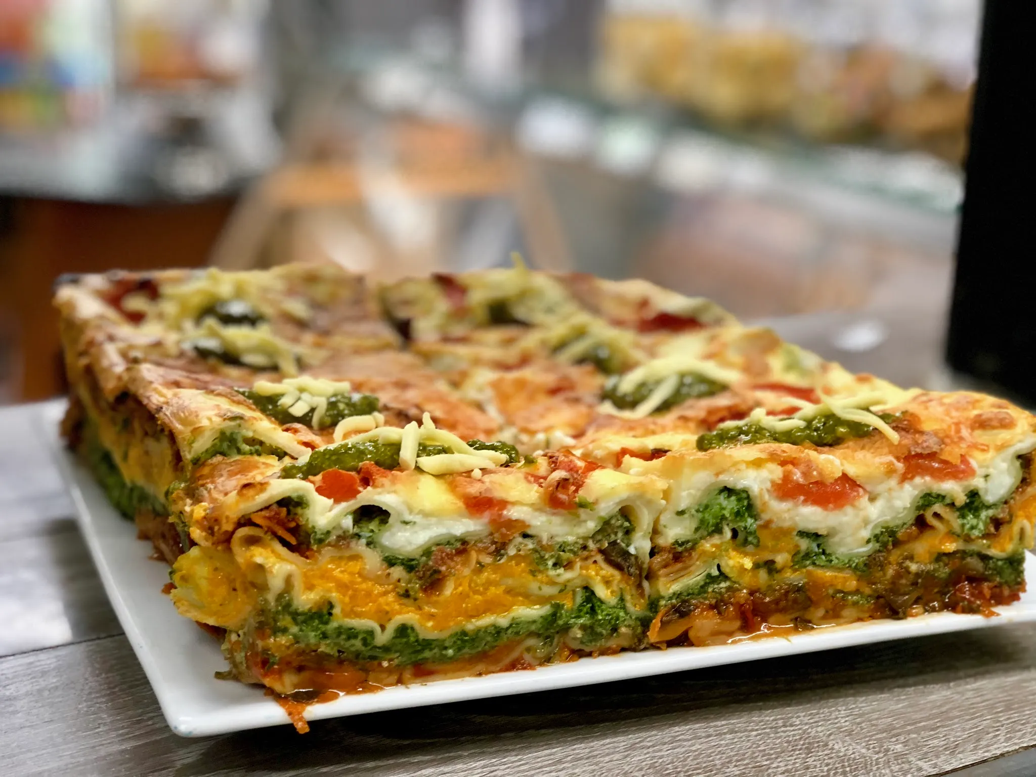 Layered vegetable lasagne on a white plate with visible spinach and melted cheese