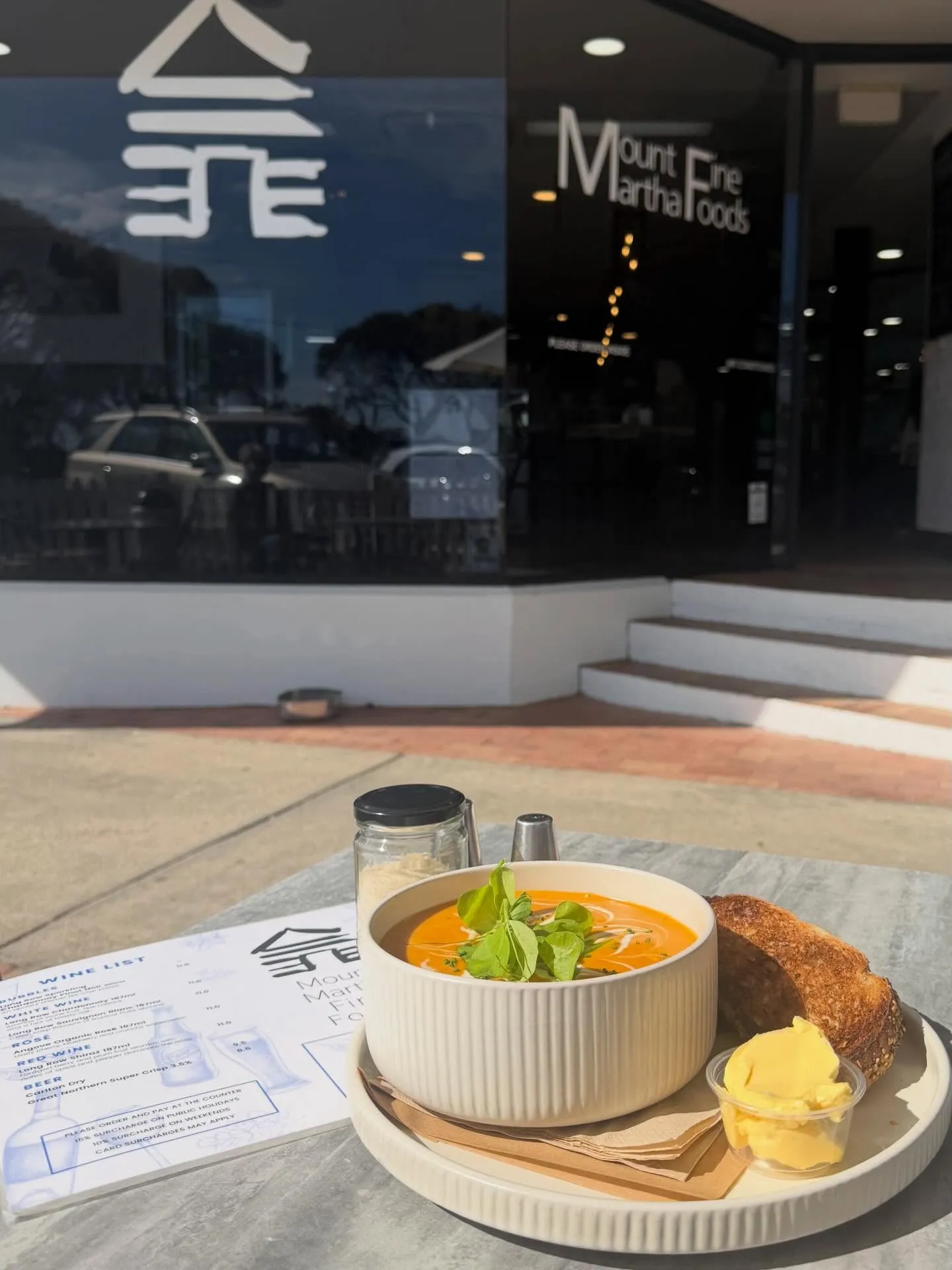 Orange pumpkin soup with cream swirl and basil on a white tray with sourdough toast